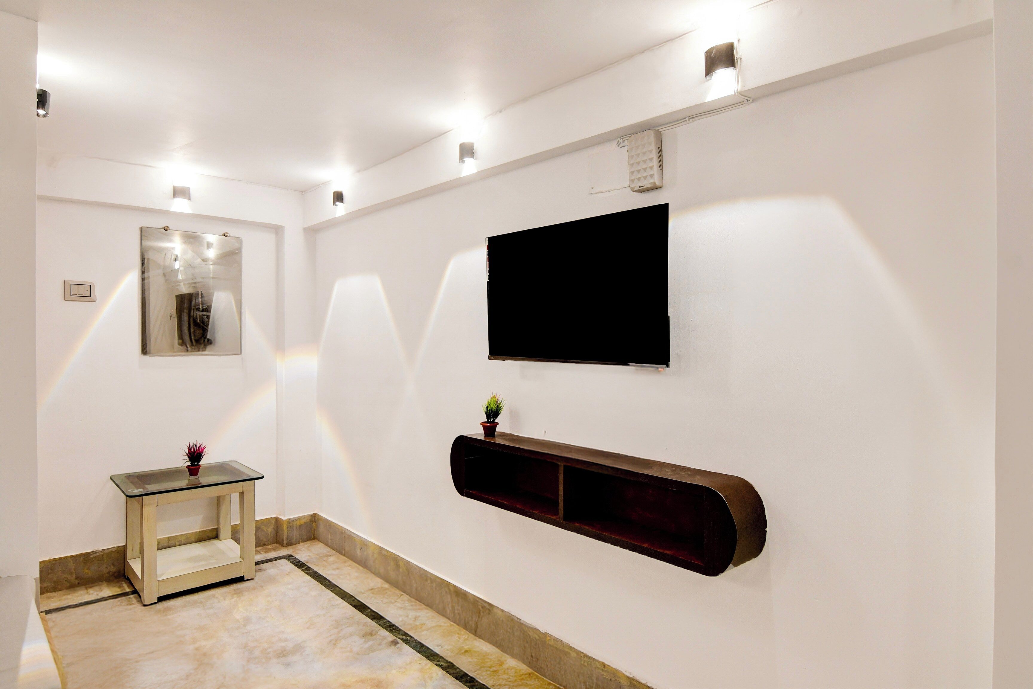 Une salle de bain moderne avec une table en verre, un téléviseur fixé au mur et une étagère intégrée.