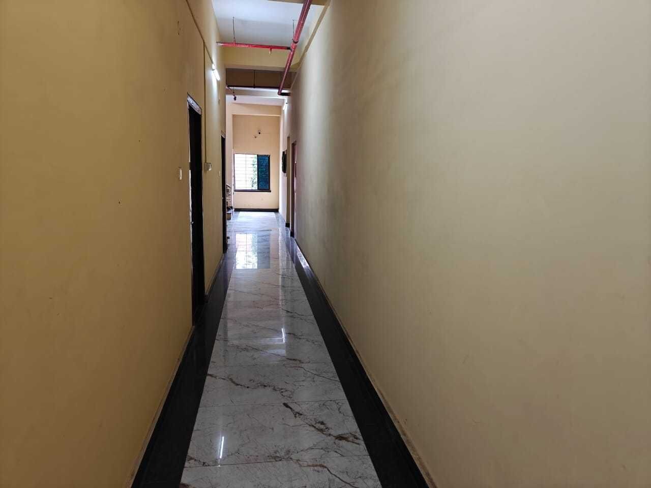 Un passadís amb sòl de marbre i parets grogues que condueix a una habitació amb finestra.