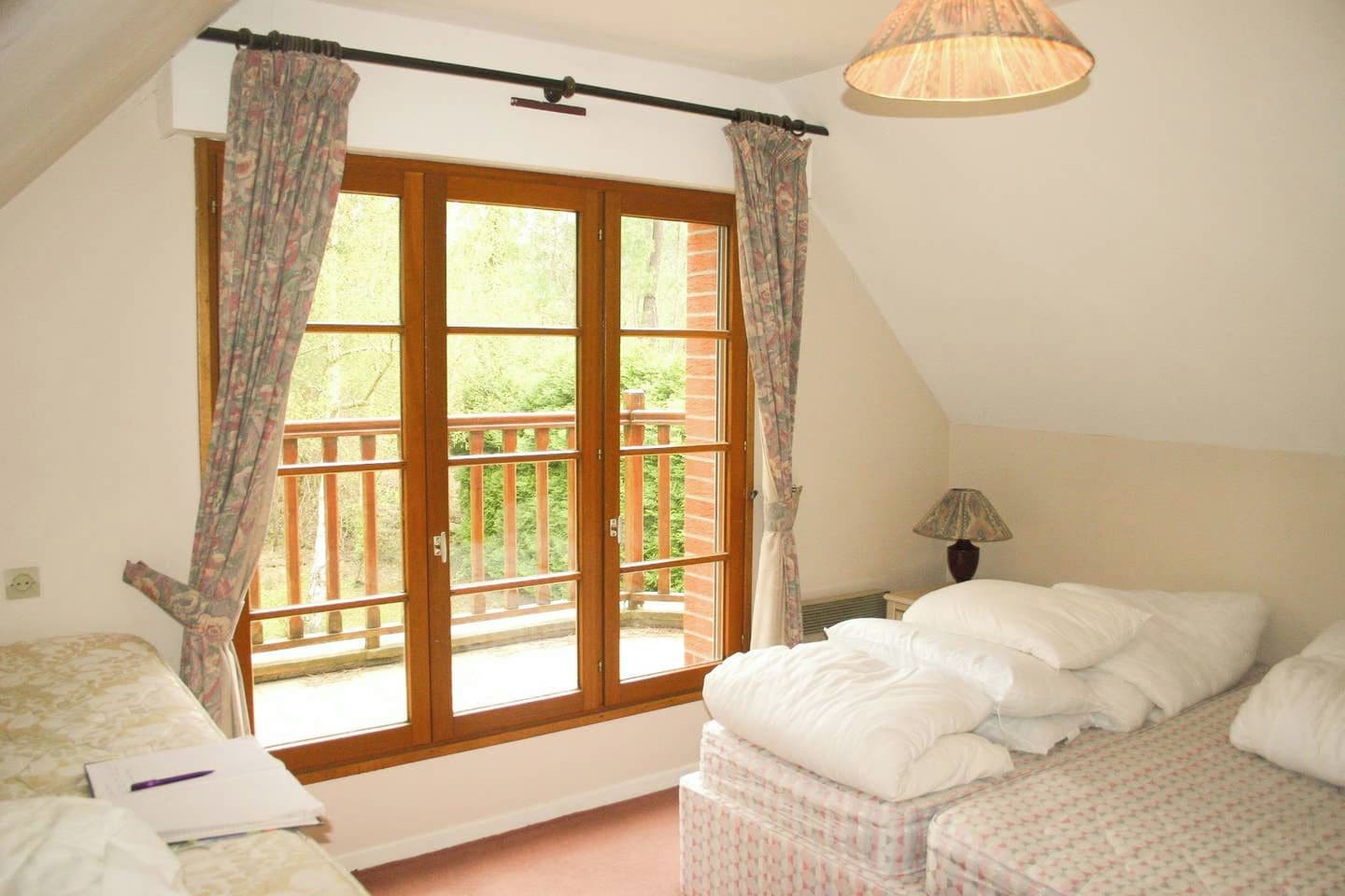 Ein Schlafzimmer mit großem Fenster, einem Bett, einem Nachttisch mit Lampe und einem Sessel.