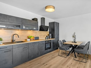 Eine moderne Küche mit dunklen Schränken, einer Holz Arbeitsplatte und einem Essbereich mit Tisch und Stühlen.