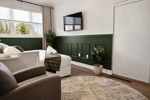 Een moderne slaapkamer met een bed, een aan de muur bevestigde televisie, een raam met gordijnen en een kamerplant.