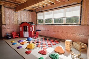 A playroom with a playhouse, mats, and wooden blocks. - Riverside Villa - Hot Tub + Games + Fire Pit (Huntsville)