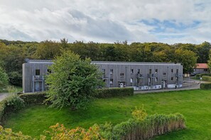 A modern building with a flat roof and multiple windows, surrounded by a well-maintained lawn and trees. - Modern vacation rental in a quiet location - Haus Fore Vacation Rental No. 202 (Lohme OT Ranzow)
