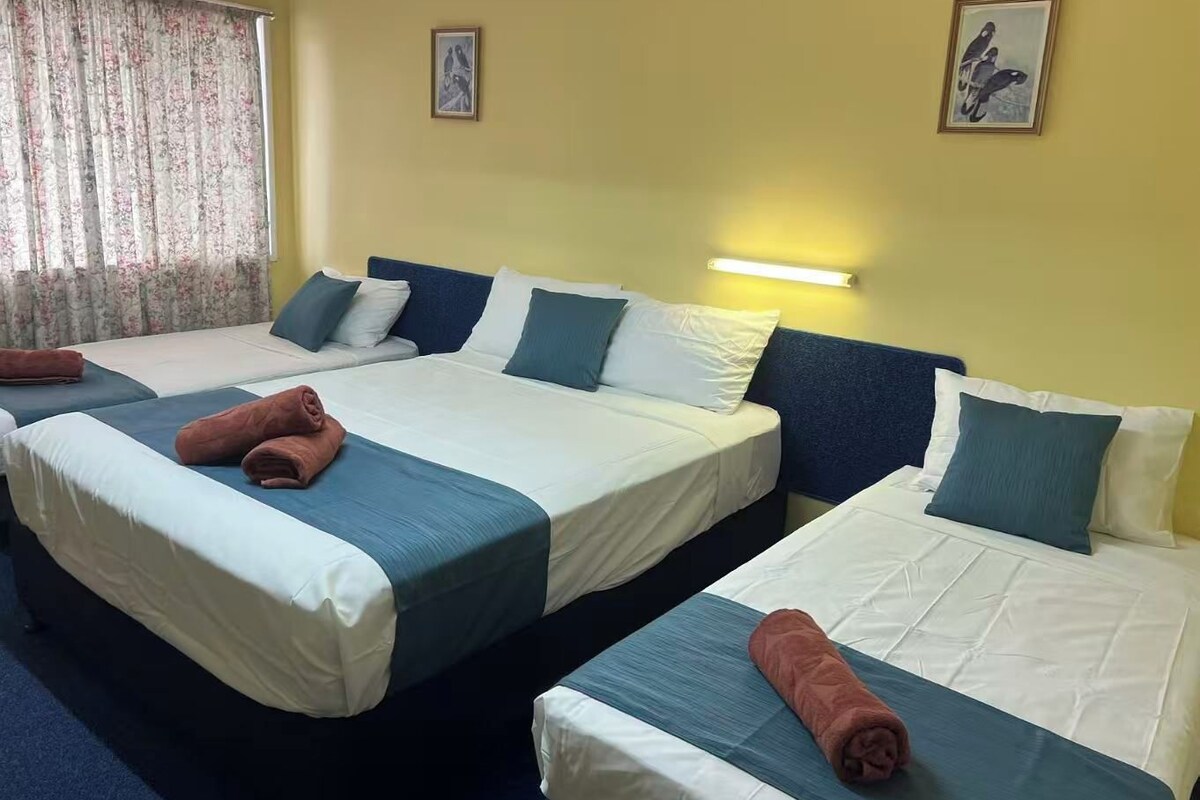 Een hotelkamer met twee bedden, elk met een deken van blauw en wit, en een paar opgerolde handdoeken.