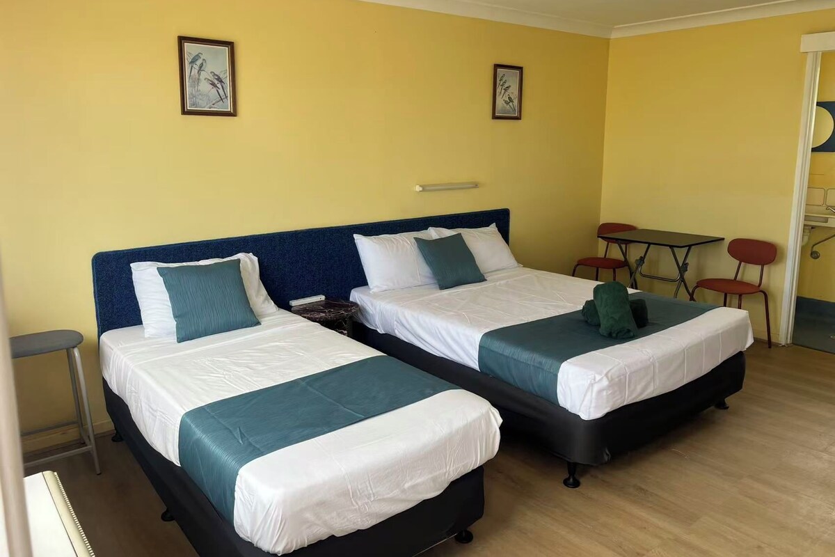 Een hotelkamer met twee bedden, een tafeltje en stoelen.
