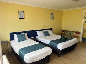 Een hotelkamer met twee bedden, een tafeltje en stoelen.