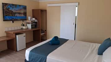 Ein Hotelzimmer mit einem Bett, einem Schreibtisch mit Mikrowelle, einem kleinen Kühlschrank und einem Bild an der Wand.