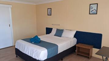 Una habitación de hotel con una cama, una mesita de noche y dos cuadros en la pared.
