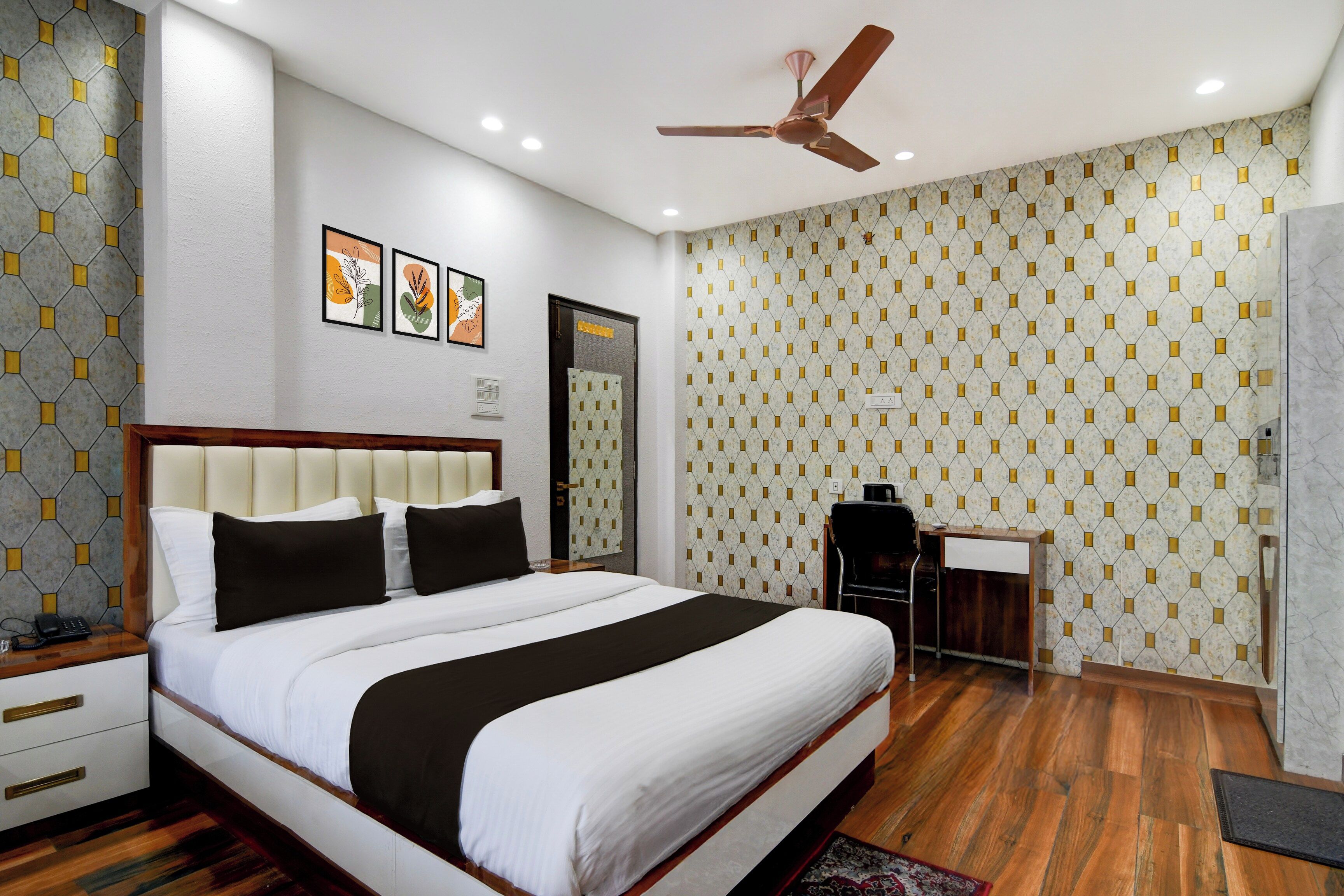 A hotel room with a large bed, a desk, a chair, and a ceiling fan.