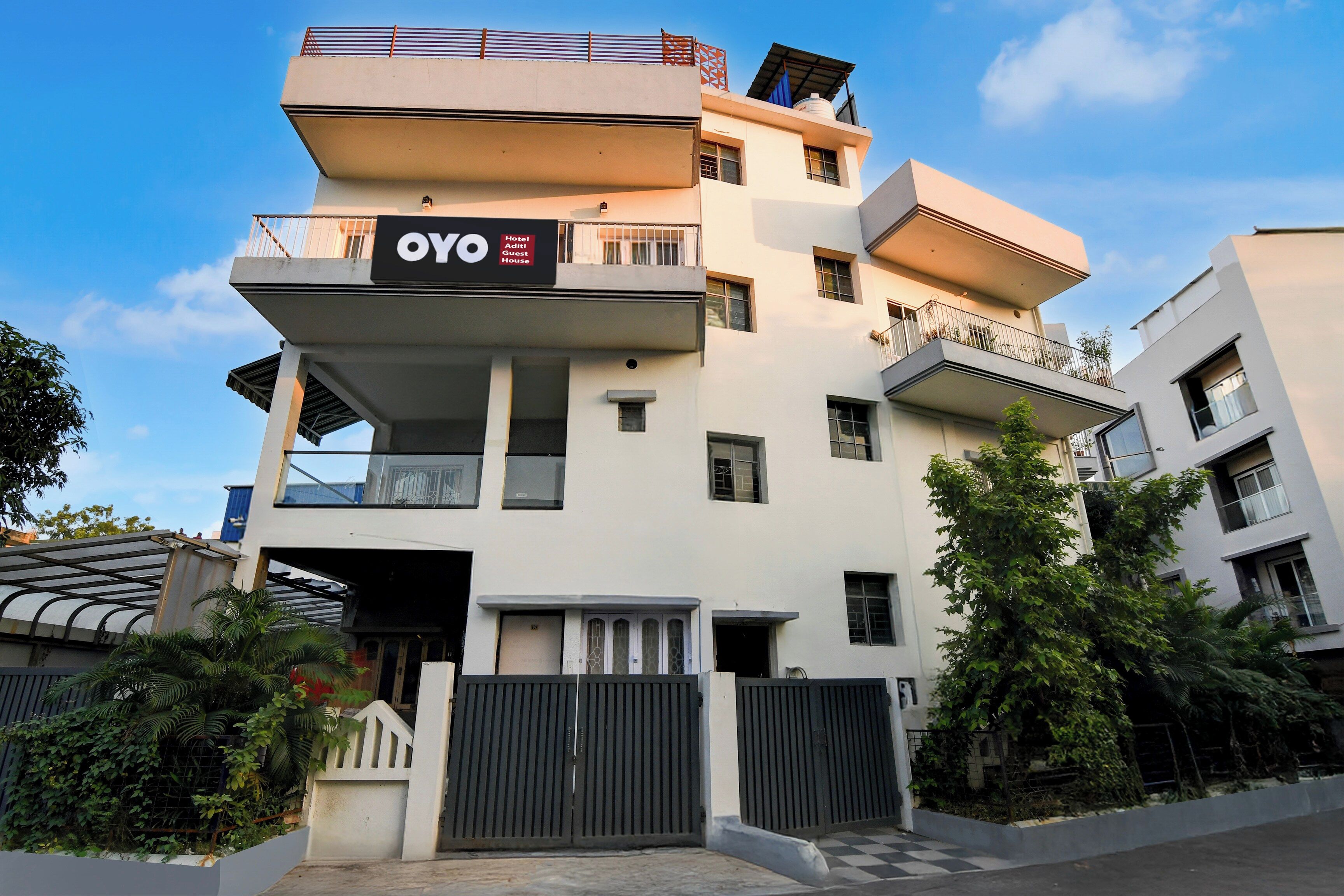 A multi-story hotel with balconies, a gated entrance, and a clear sky.