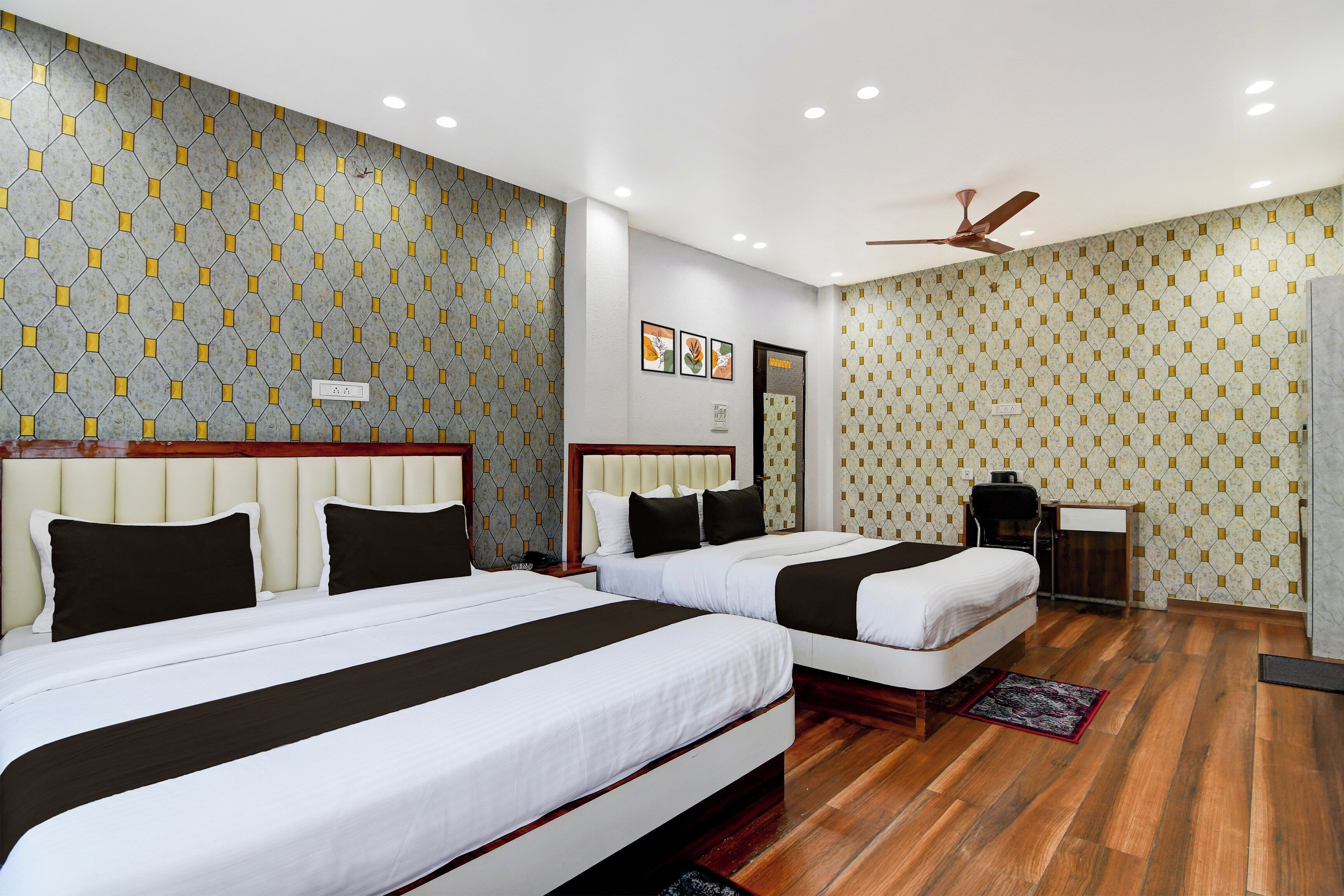 A hotel room with two beds, a ceiling fan, and a patterned wall.
