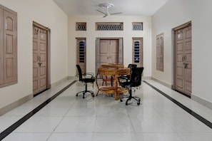 A spacious room with a tiled floor, a ceiling fan, and a dining table with chairs.