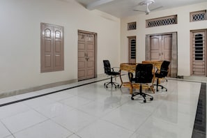 A spacious room with a tiled floor, a table with chairs, and a ceiling fan. - Hotel O by OYO Green Eco Space (Kolkata)