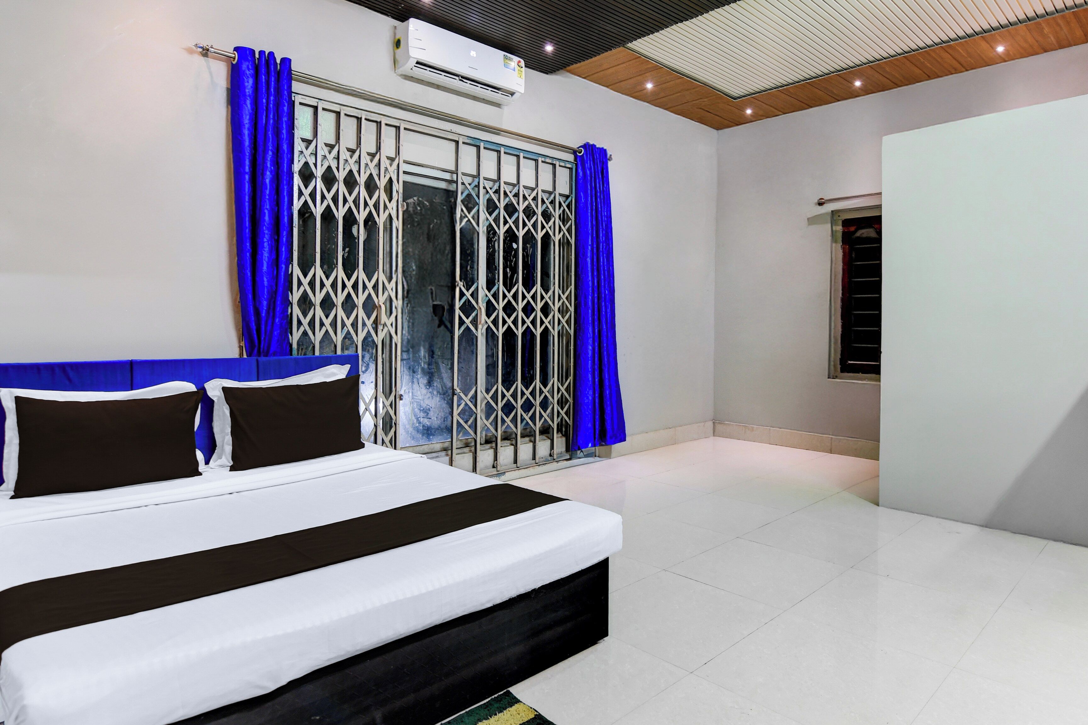 Un dormitorio con cama, cortinas y unidad de aire acondicionado.