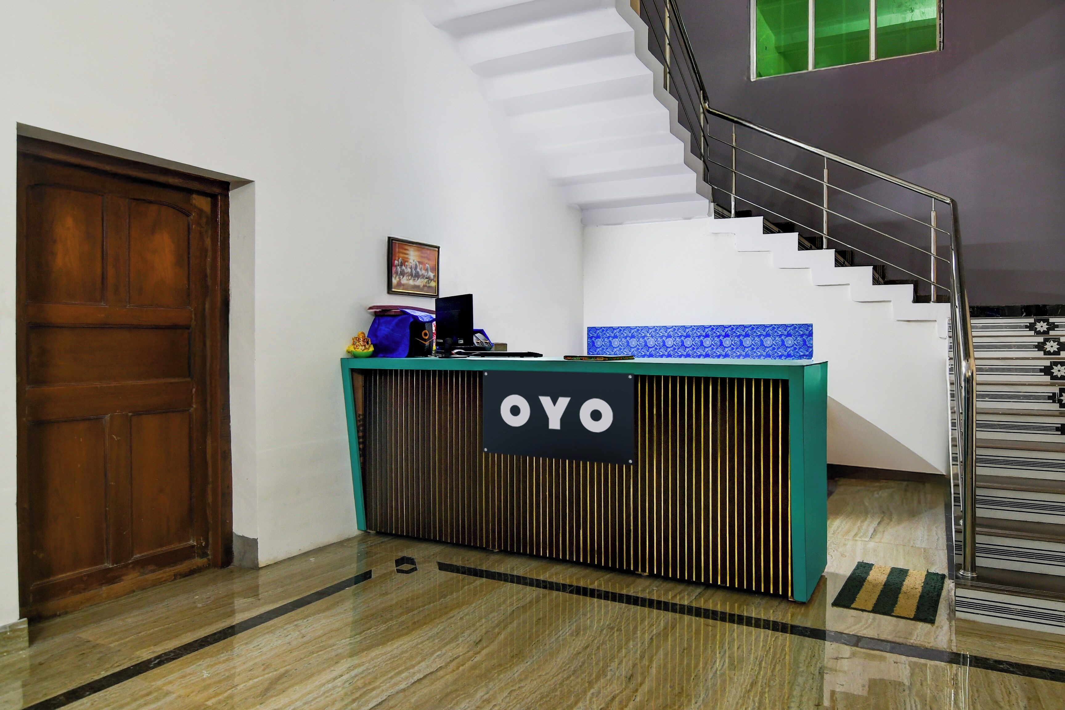 Um balcão de recepção com uma placa indicando 'OYO', uma escadaria e uma porta.