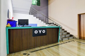 A reception desk with a sign that reads 'OYO' in a modern building with a staircase and a marble floor. - Hotel O by OYO Green Eco Space (Kolkata)