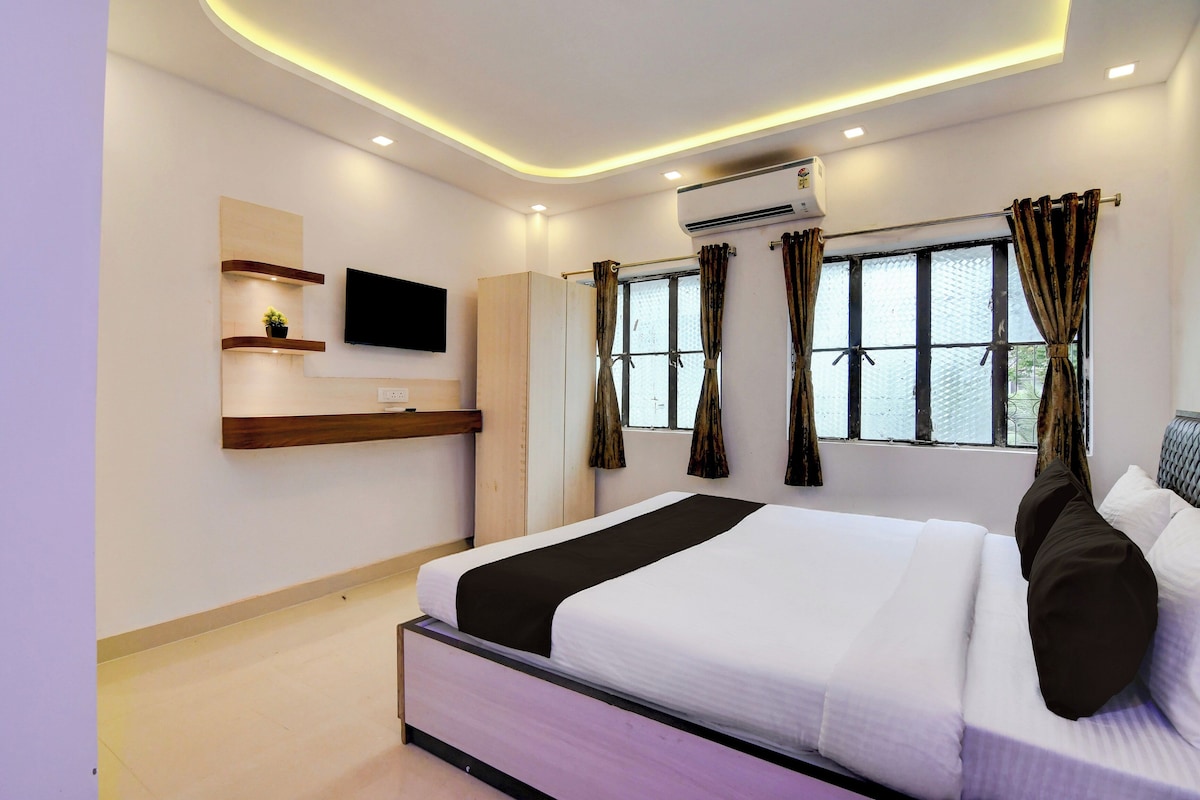 A modern bedroom with a bed, a TV, a wardrobe, and a window with curtains.