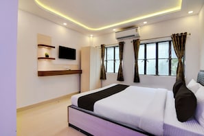 A modern bedroom with a bed, a TV, a wardrobe, and a window with curtains. - Hotel O by OYO Acroview (Kolkata)