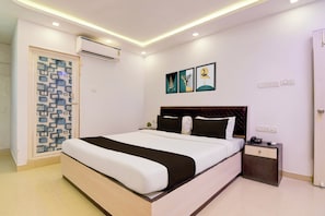 A modern hotel room with a large bed, bedside tables, an air conditioning unit, and artwork on the wall. - Hotel O by OYO Acroview (Kolkata)