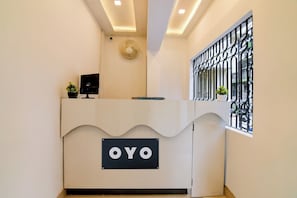 A reception desk with a sign that reads 'OYO' and a window with a metal grill. - Hotel O by OYO Acroview (Kolkata)