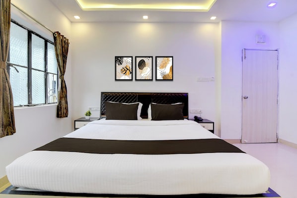 A modern bedroom with a large bed, a headboard with a diamond-patterned design, and three framed artworks on the wall. - Hotel O by OYO Acroview (Kolkata)