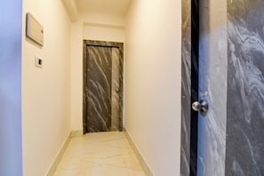Un pasillo con piso de mármol que conduce a una puerta con una placa de número.