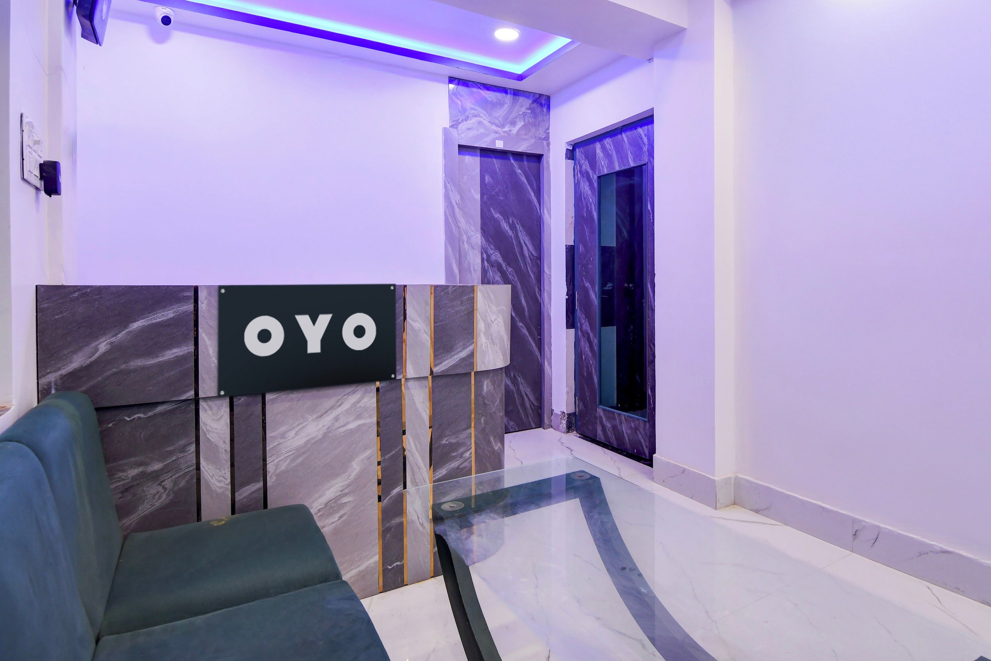 A hotel reception area with a marble reception desk, a sofa, and a large window.
