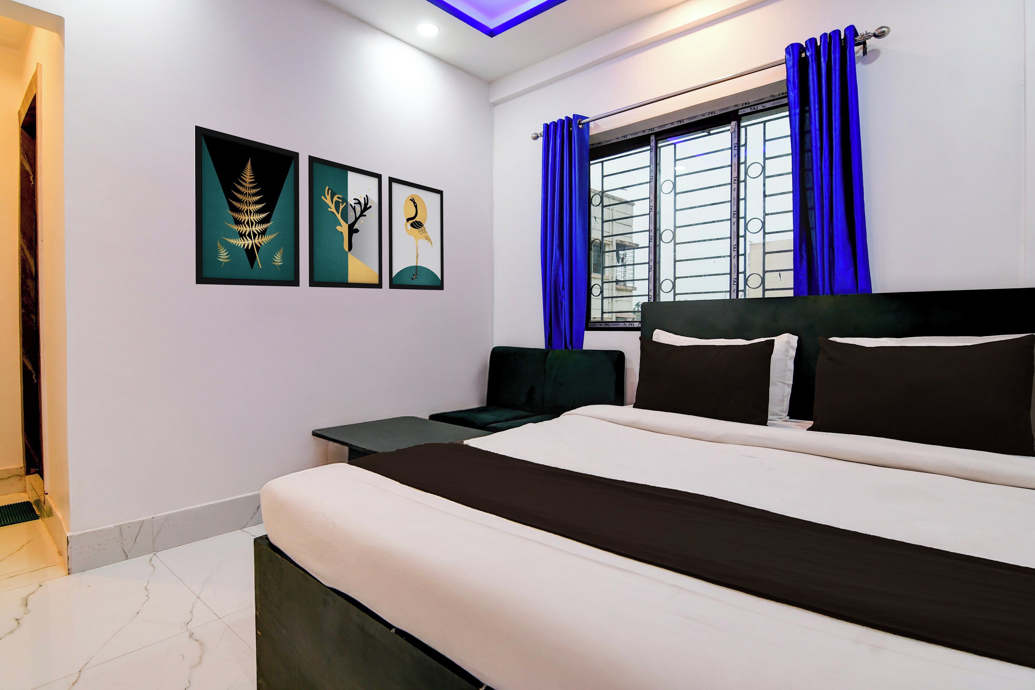 A bedroom with a bed, a nightstand, a window with curtains, and wall art.