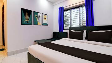 A bedroom with a bed, a nightstand, a window with curtains, and wall art.