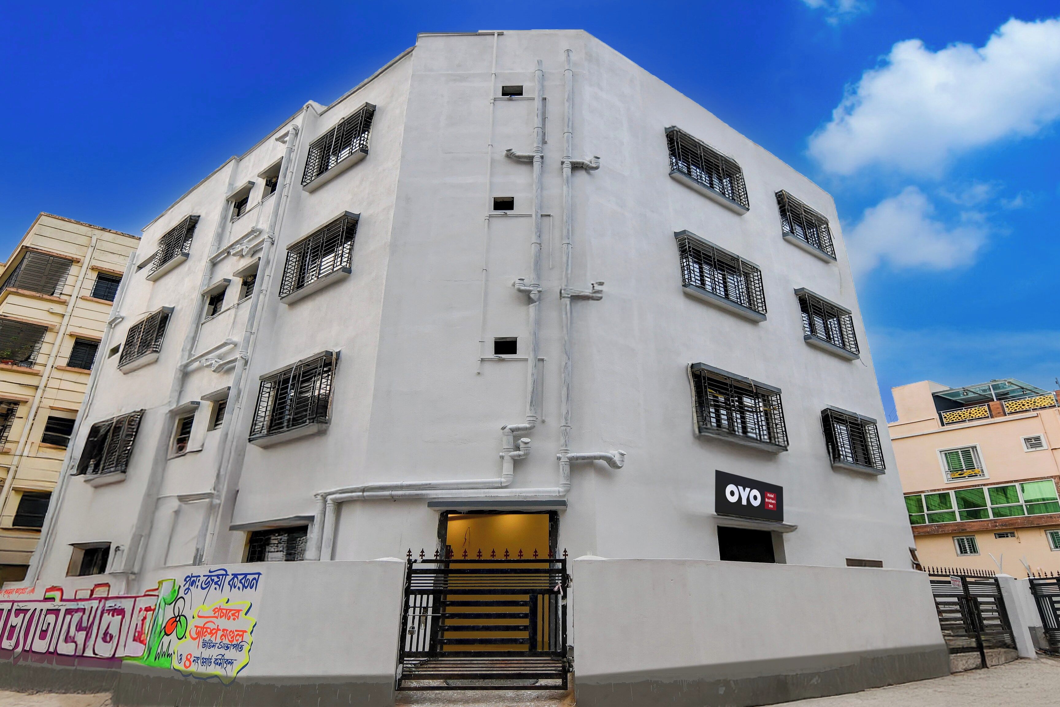 A multi-story hotel with a flat facade, multiple windows with metal grilles, and a visible entrance with a staircase.