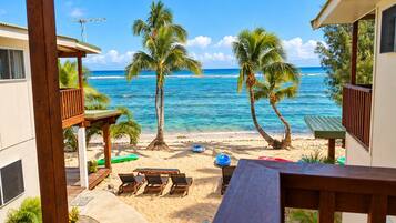 A beach view with a wooden deck, lounge chairs, and a table.