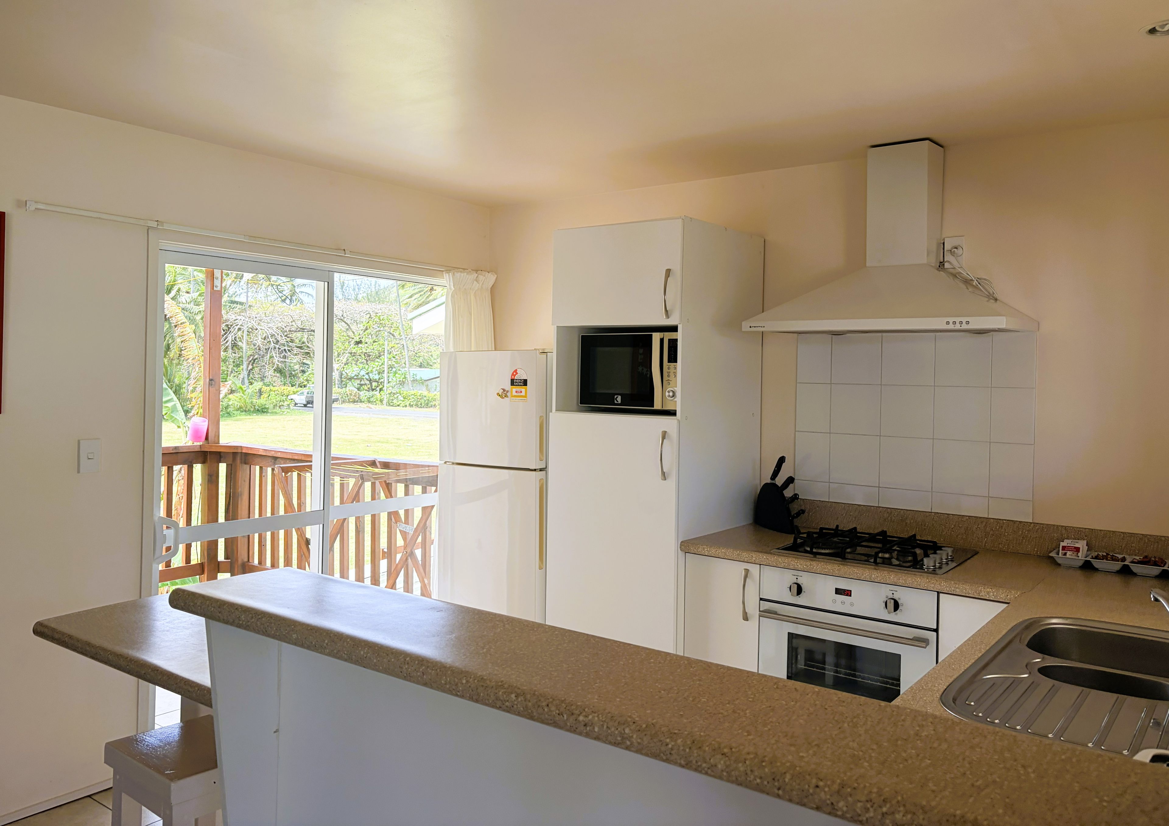 A compact kitchen with a refrigerator, microwave, stove, and sink.