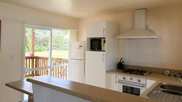 A compact kitchen with a refrigerator, microwave, stove, and sink.