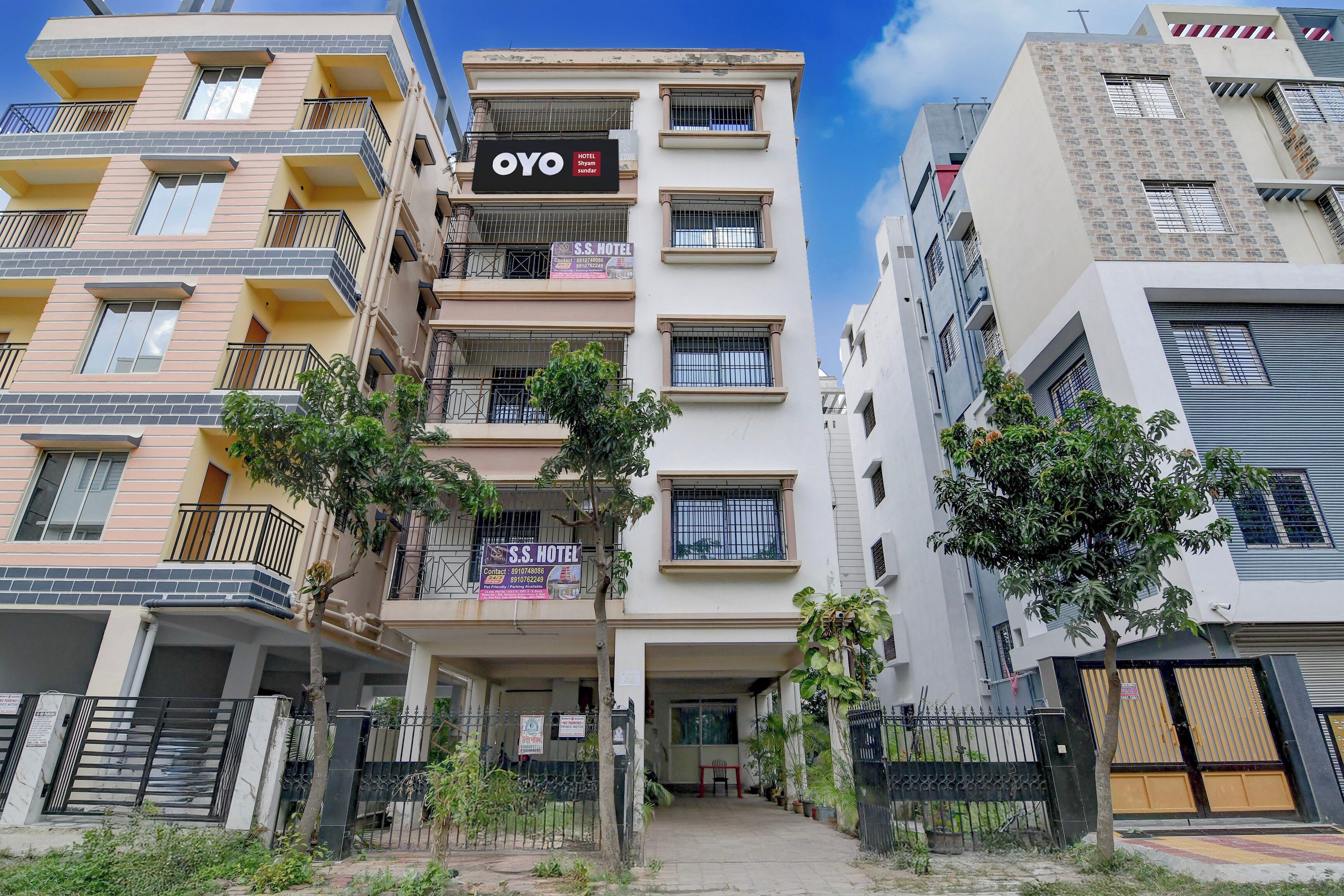 A multi-story hotel building with balconies, a sign for 'OYO HOTEL Shyam Sundar,' and a gated entrance.