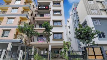 A multi-story hotel building with balconies, a sign for 'OYO HOTEL Shyam Sundar,' and a gated entrance.