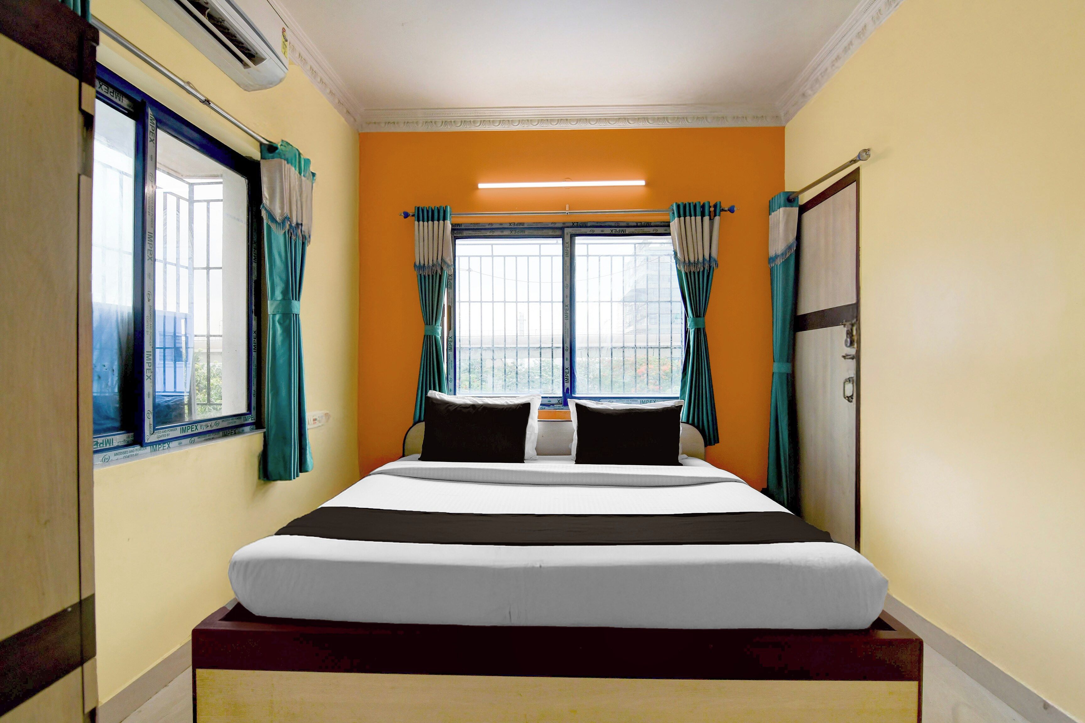 A hotel room with a bed, curtains, and a window.