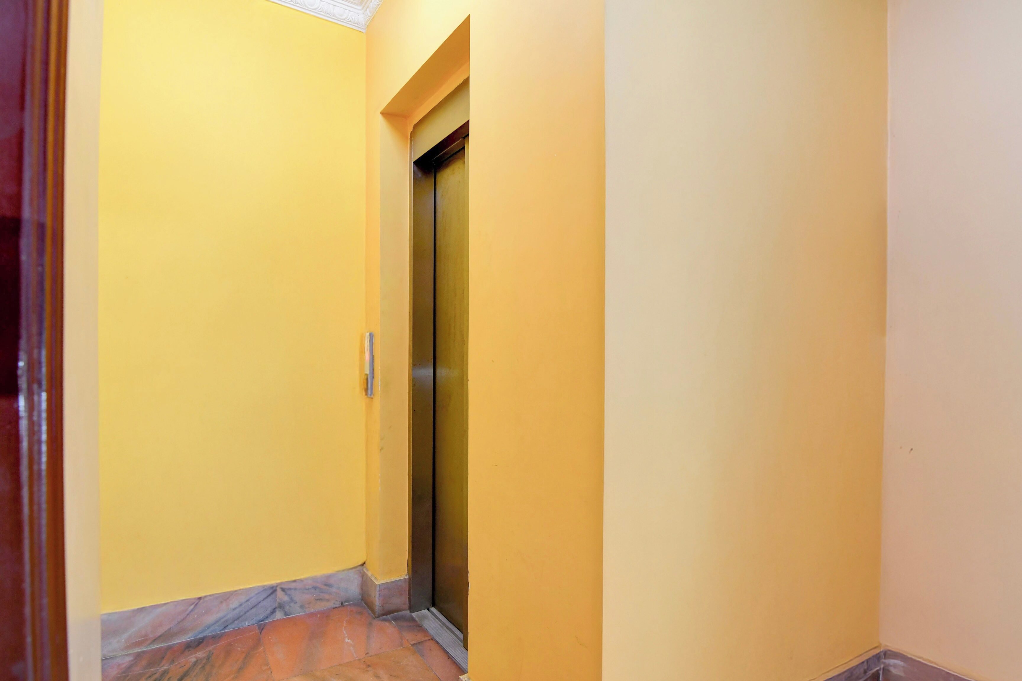 A narrow hallway with yellow walls and a marble-tiled floor.