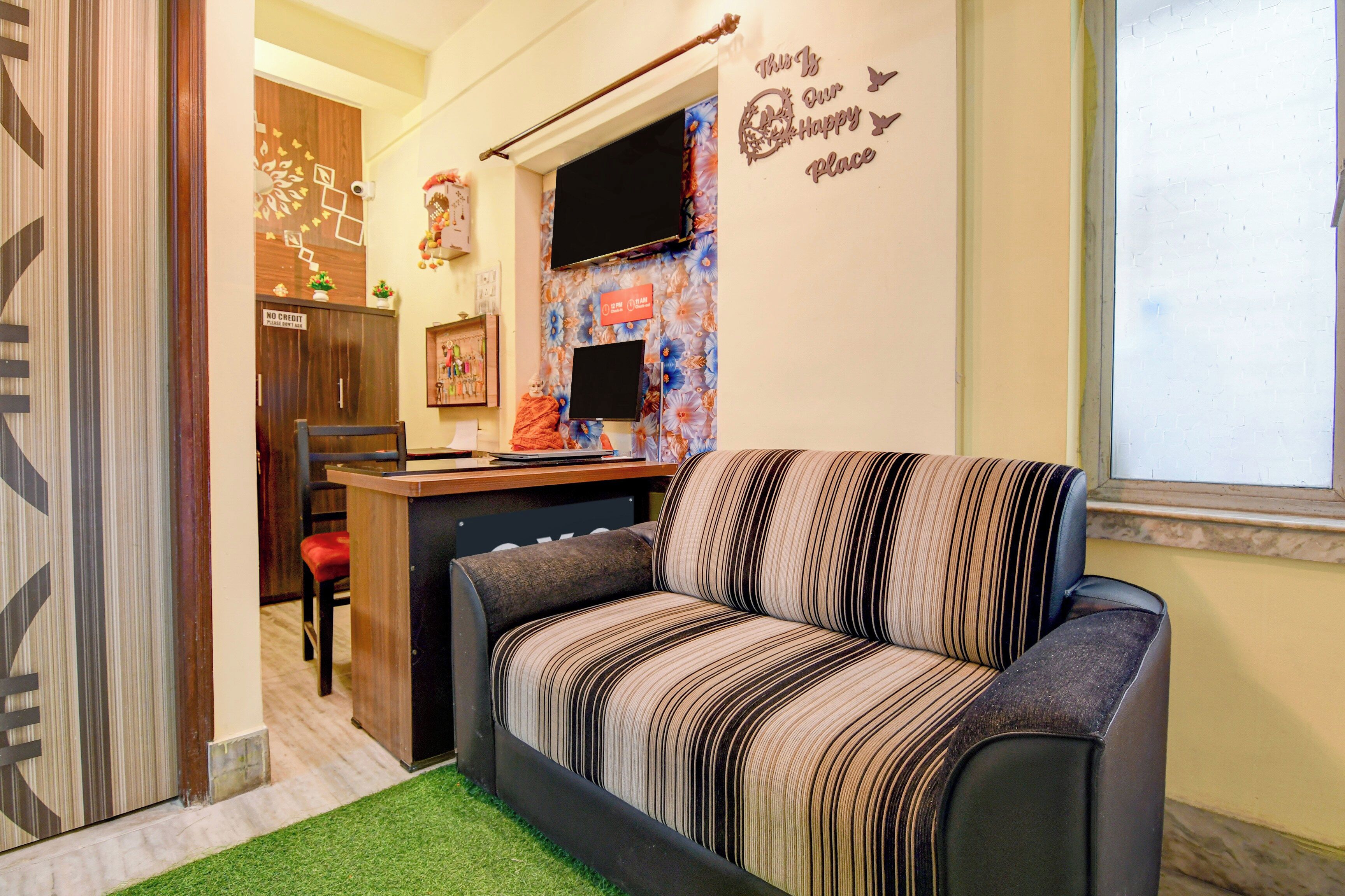 A cozy living area with a striped sofa, a small desk, and a decorative wall.
