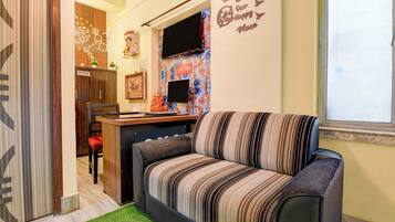 A cozy living area with a striped sofa, a small desk, and a decorative wall.
