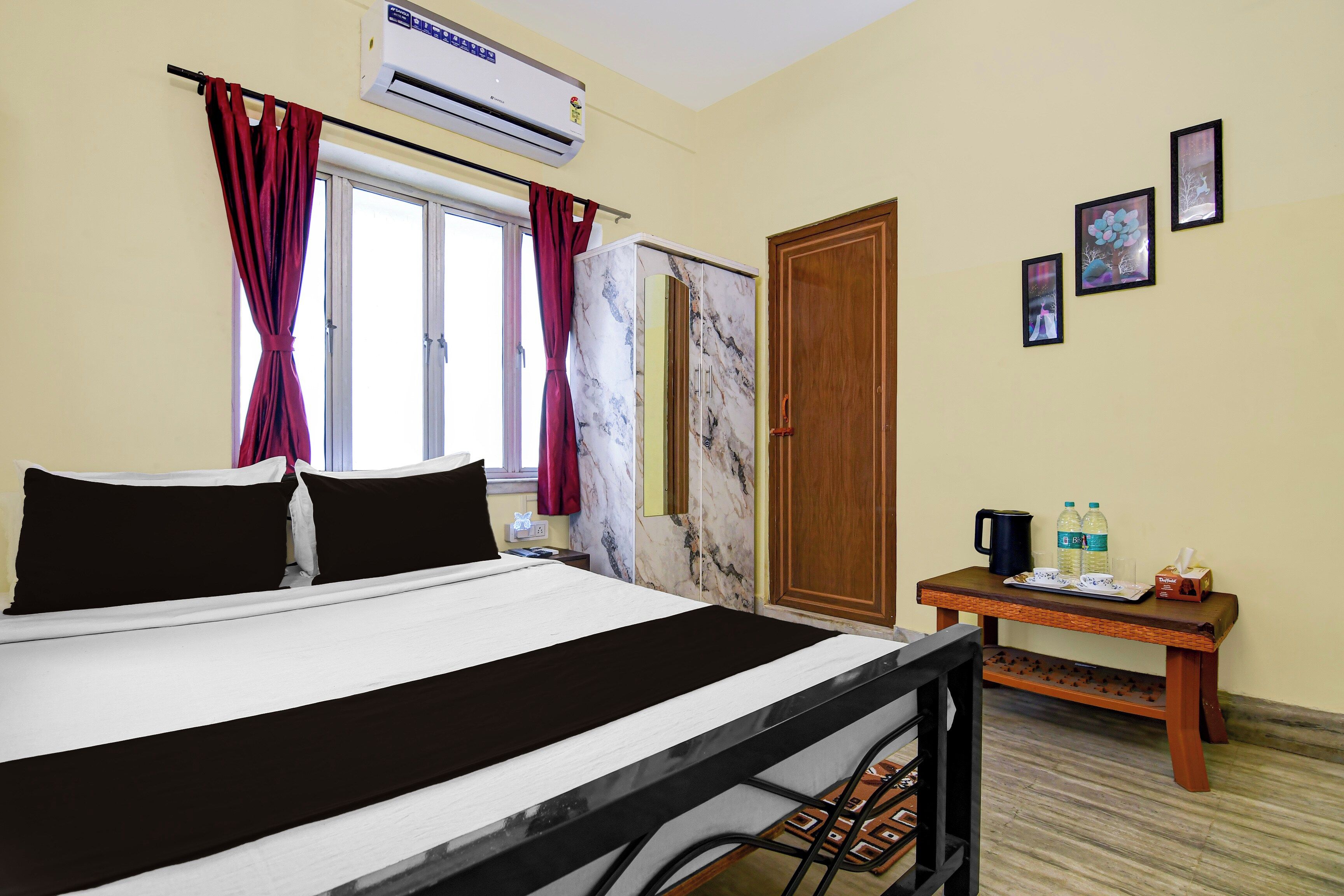 Une chambre d’hôtel comprenant un lit, un climatiseur, une armoire, une petite table avec un plateau, et une porte.