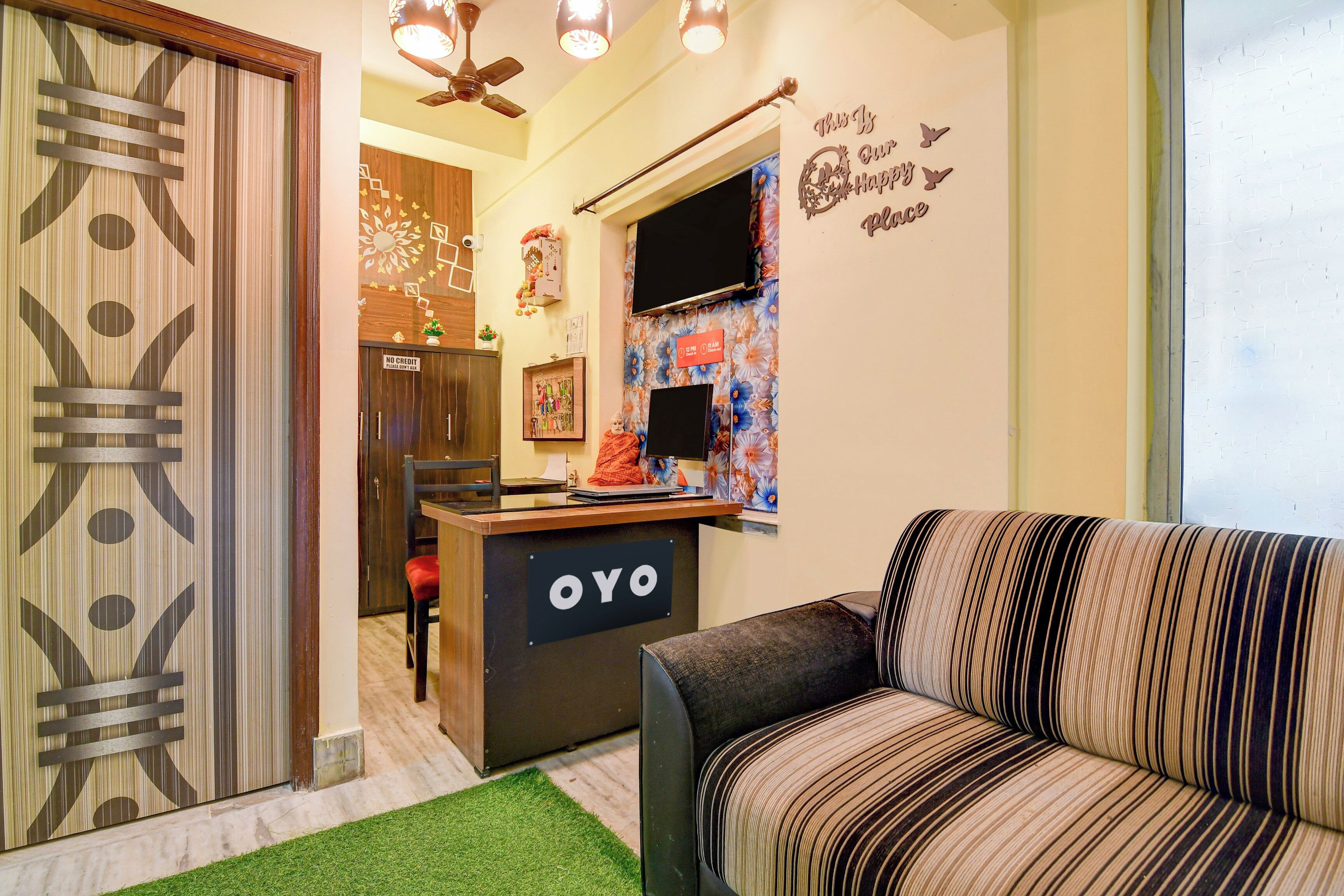 Ein Hotel-Rezeptionsbereich mit einer Couch, einem Schreibtisch und einem Schild mit der Aufschrift 'OYO'.
