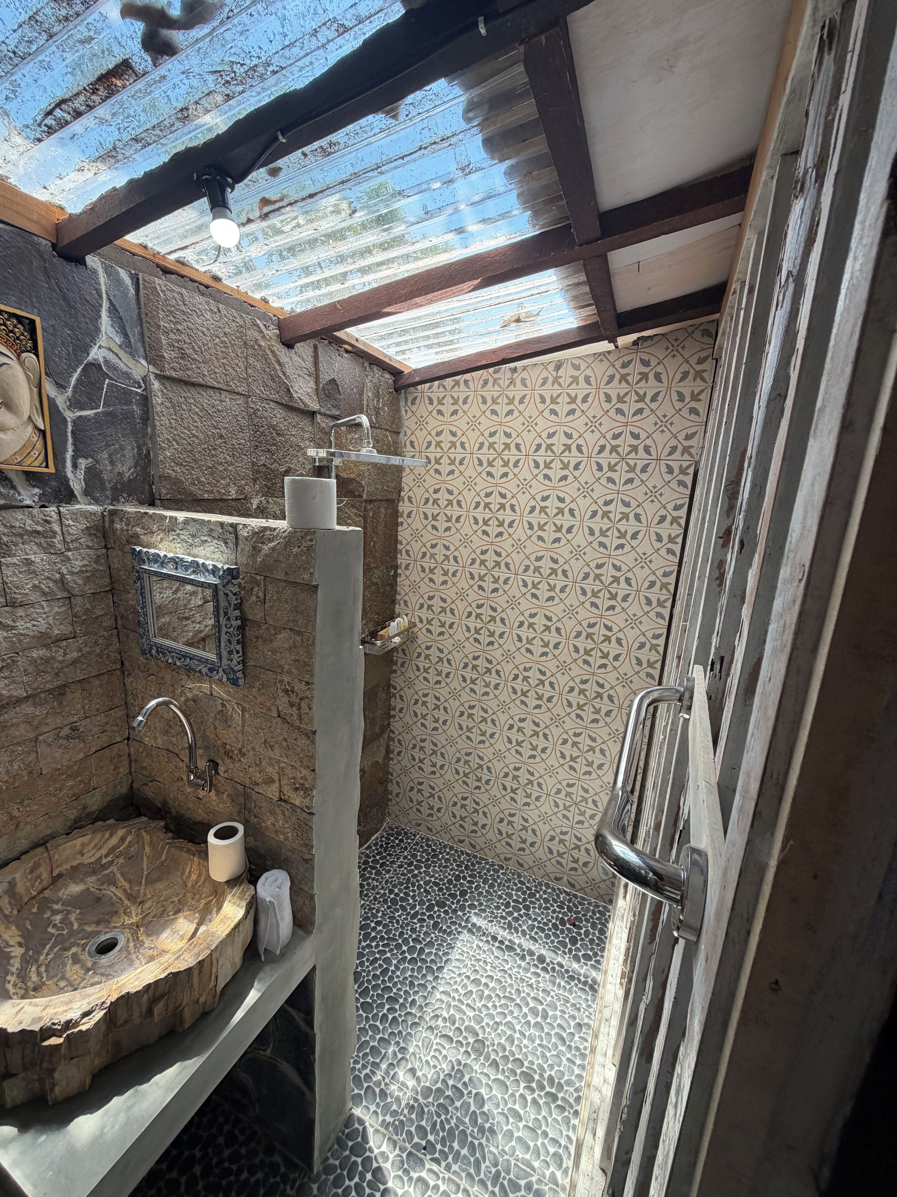 A bathroom with a stone sink, a mirror, and a shower area.