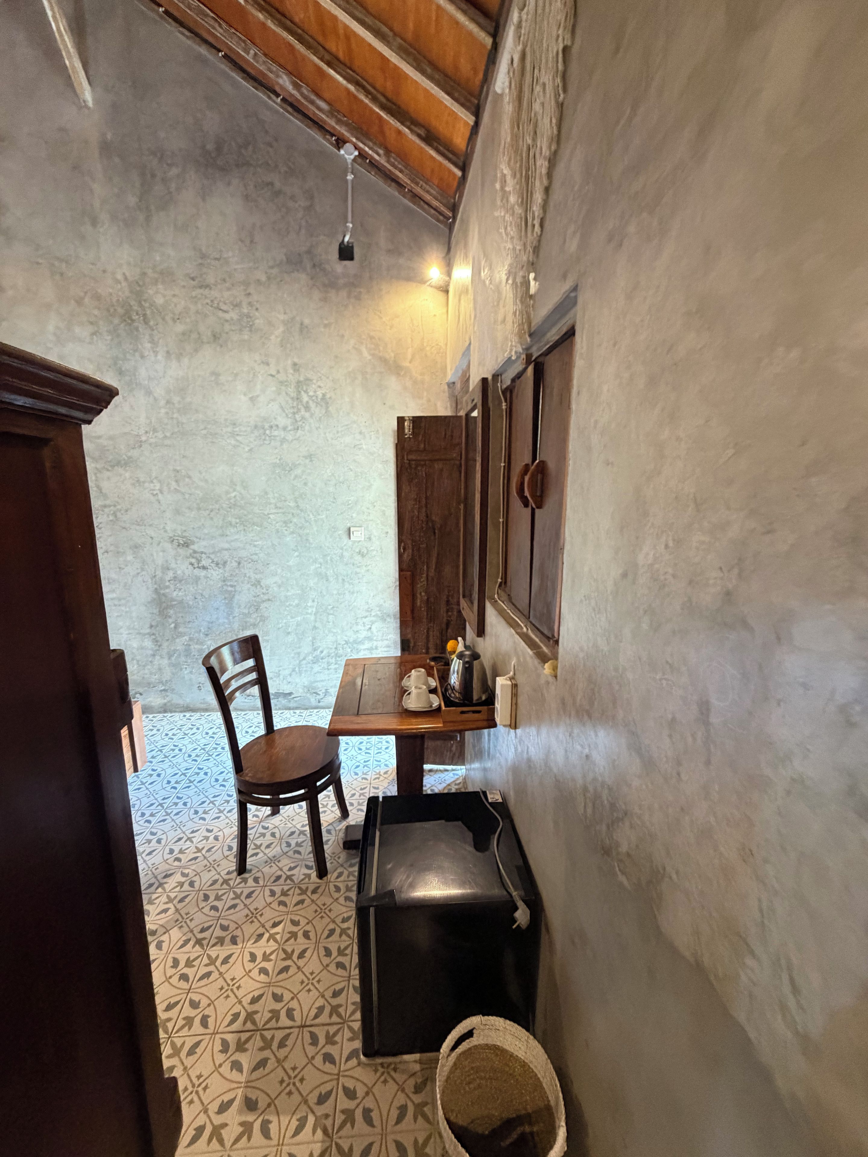Una habitación pequeña con una mesa de madera, una silla, un armario y un piso con diseño.