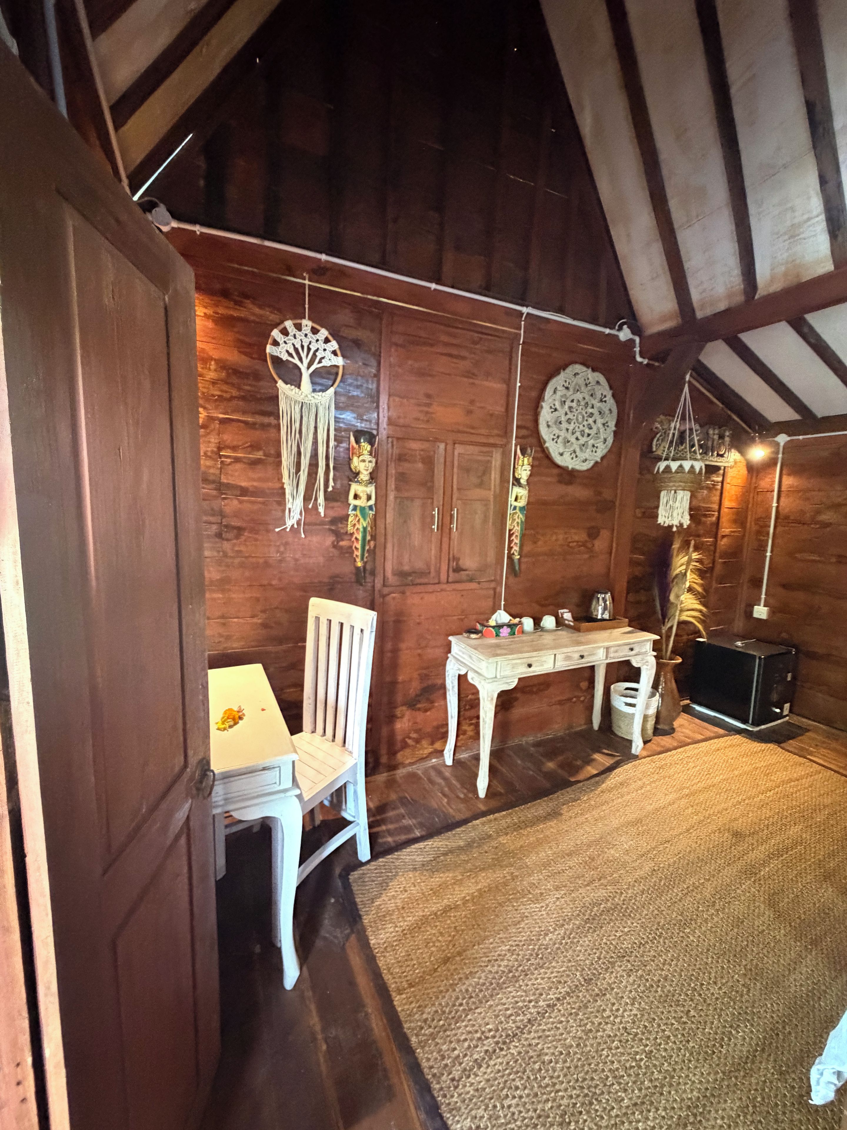 Ein rustikaler Holzraum mit schrägem Dach, einem weißen Tisch mit Stühlen, einem kleinen Fernseher und Wanddekorationen.