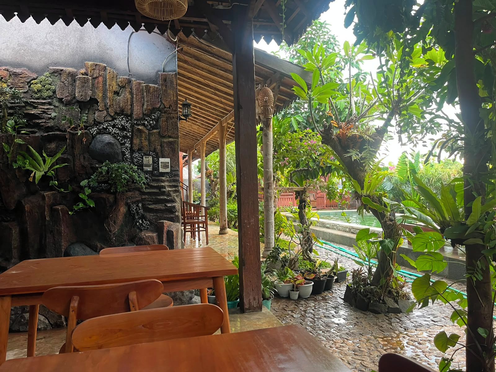 A covered outdoor seating area with stone walls and potted plants.