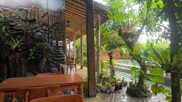 A covered outdoor seating area with stone walls and potted plants.