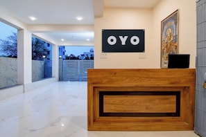 En receptionsdisk med en skylt som visar texten ”OYO” och en inramad bild ovanför.