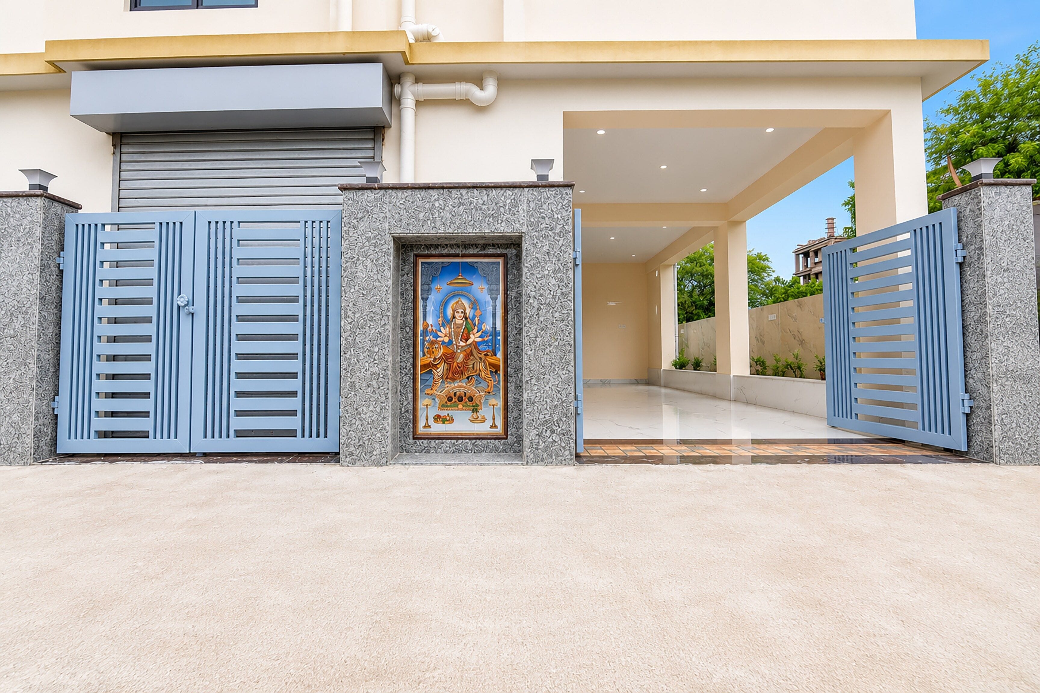 A modern house with a gated entrance, a decorative religious icon, and a well-maintained garden.