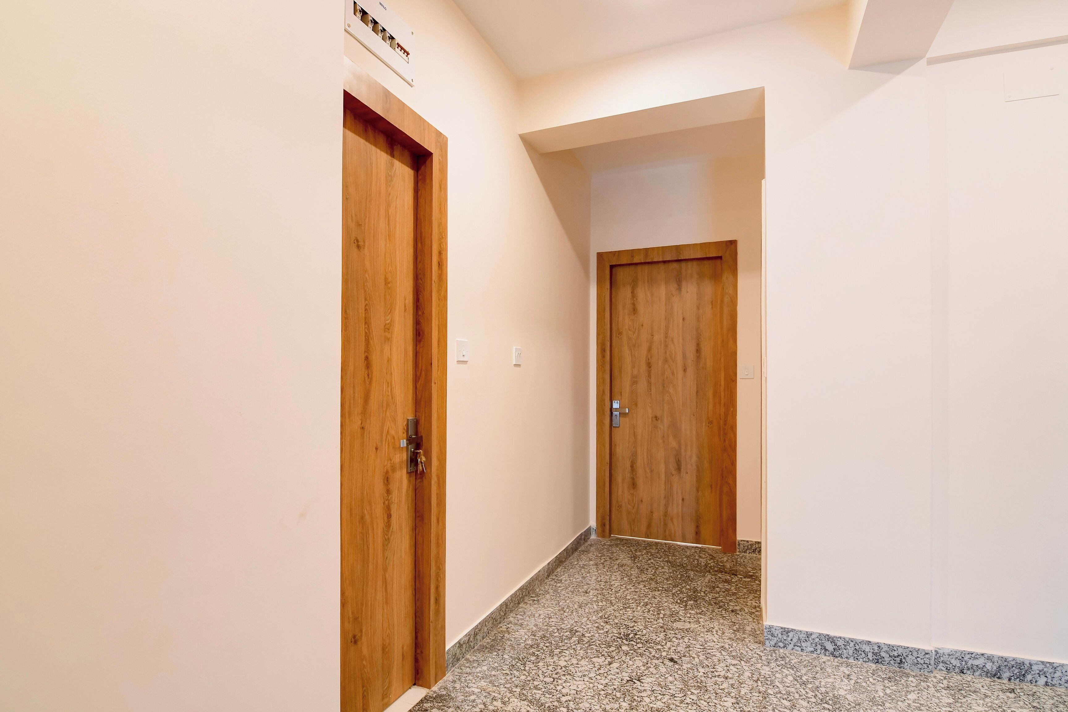 A hallway with wooden doors and a speckled floor.