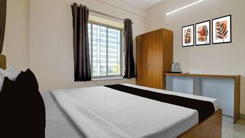 A hotel room with a bed, a desk, and a window with curtains.